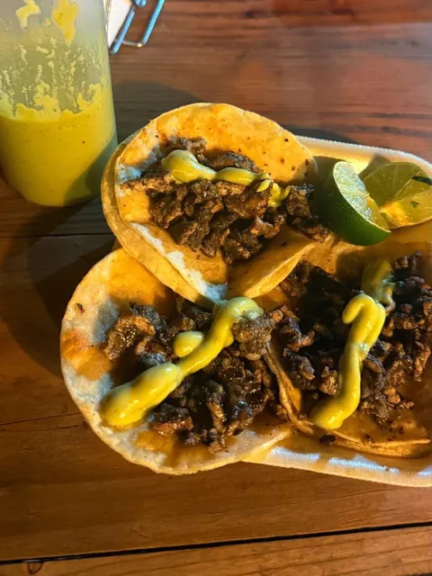Tacos de trompo negro con salsa de aguacate sobre la mesa, con su salsa de la casa